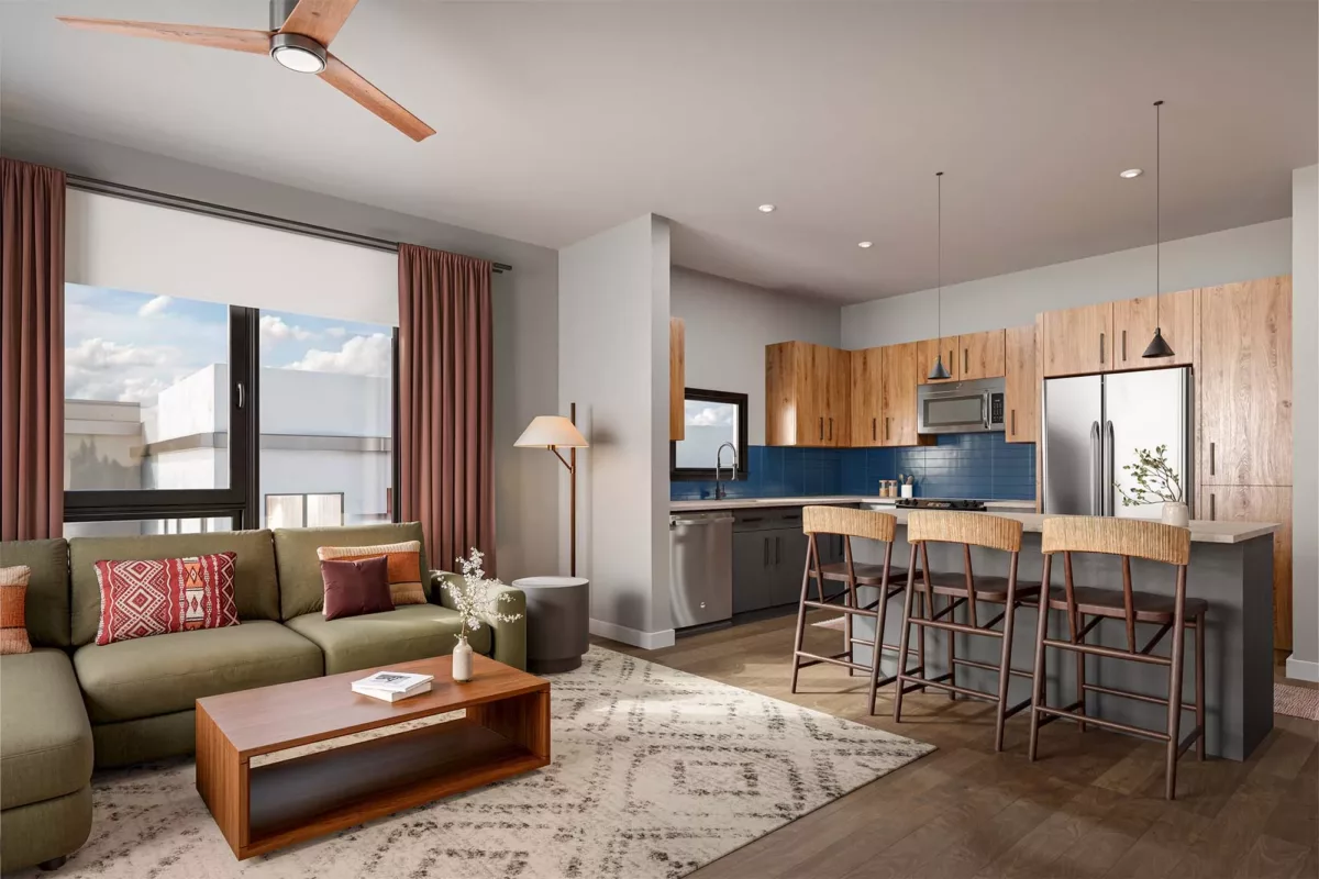 Open kitchen and living area with wood cabinetry, island seating, and large bright windows.